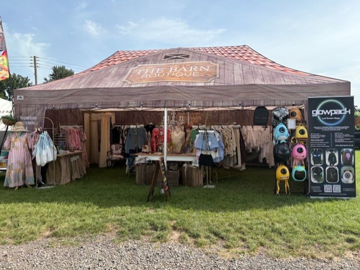 Gala Tent gazebo printed to look like a wooden barn, branded The Barn Boutique, selling women's clothing at an outdoor show