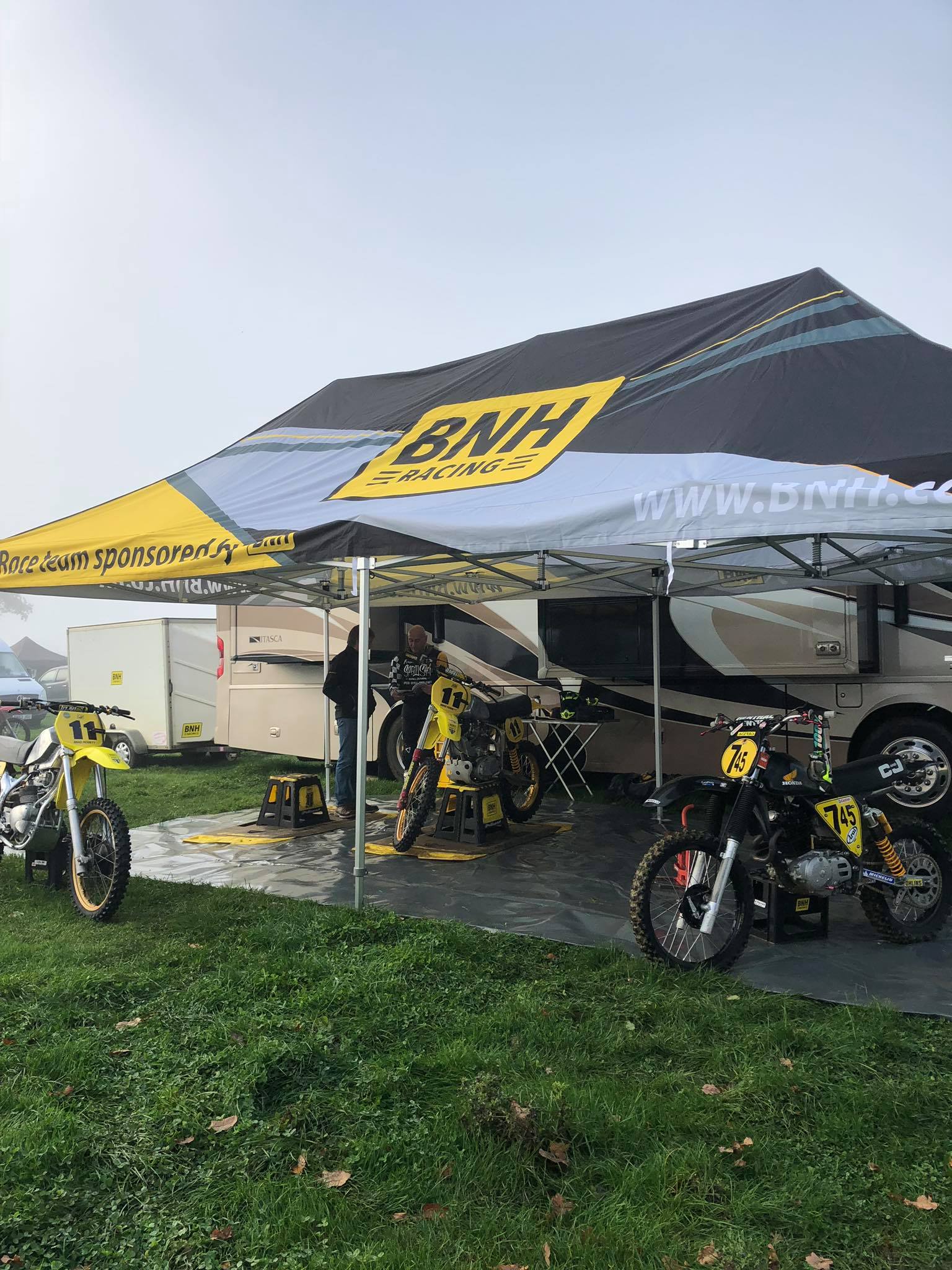 Jet-washing a muddy motocross bike beside the pit