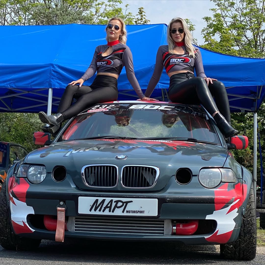 Branded drift team awning with sponsor graphics and crowd barriers