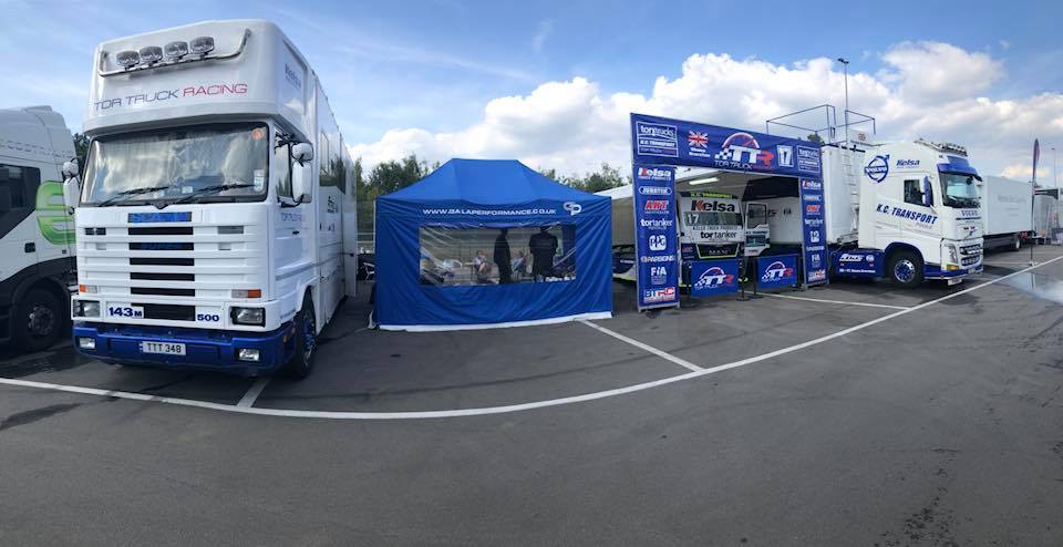 Heavy-duty freestanding motorsport awning forming a race compound