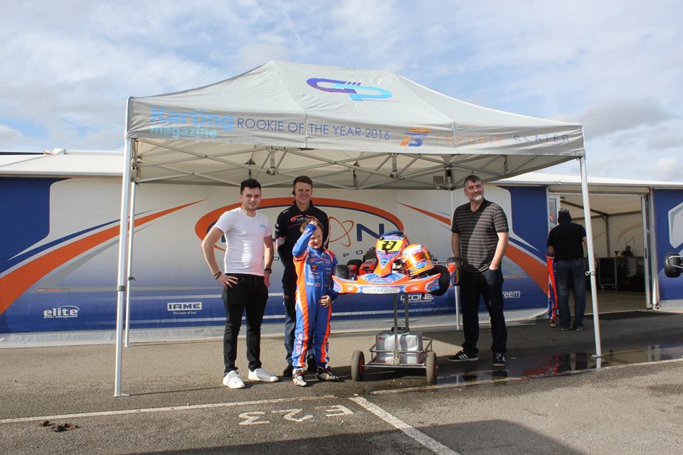 Kart on a trolley under a pop up awning in a club paddock