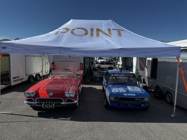 Rallycross team working on a car between heats under an awning