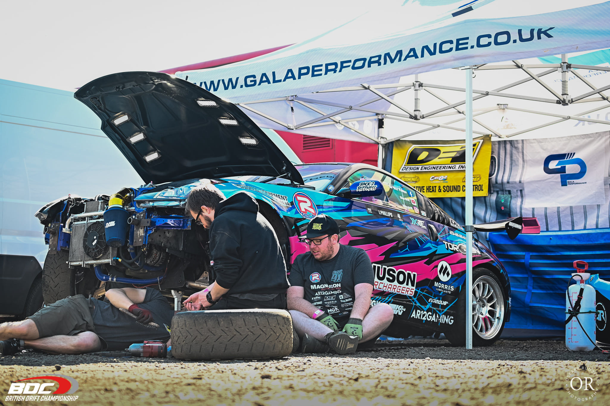 Team changing a tyre under a pop up race gazebo