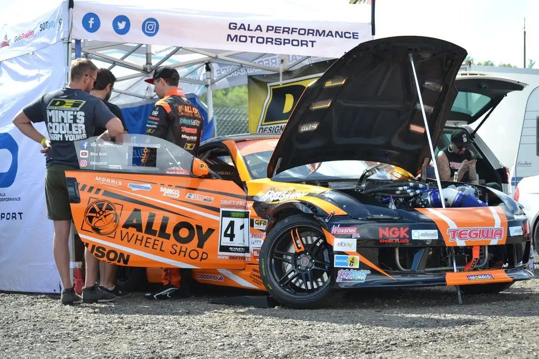 Team working on a race car under a pop up race tent