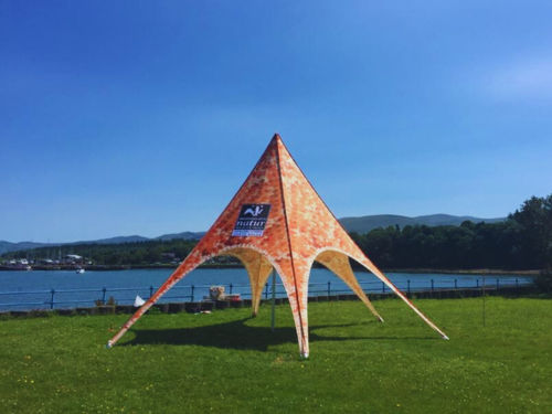 branded star shade on the grass by a lake