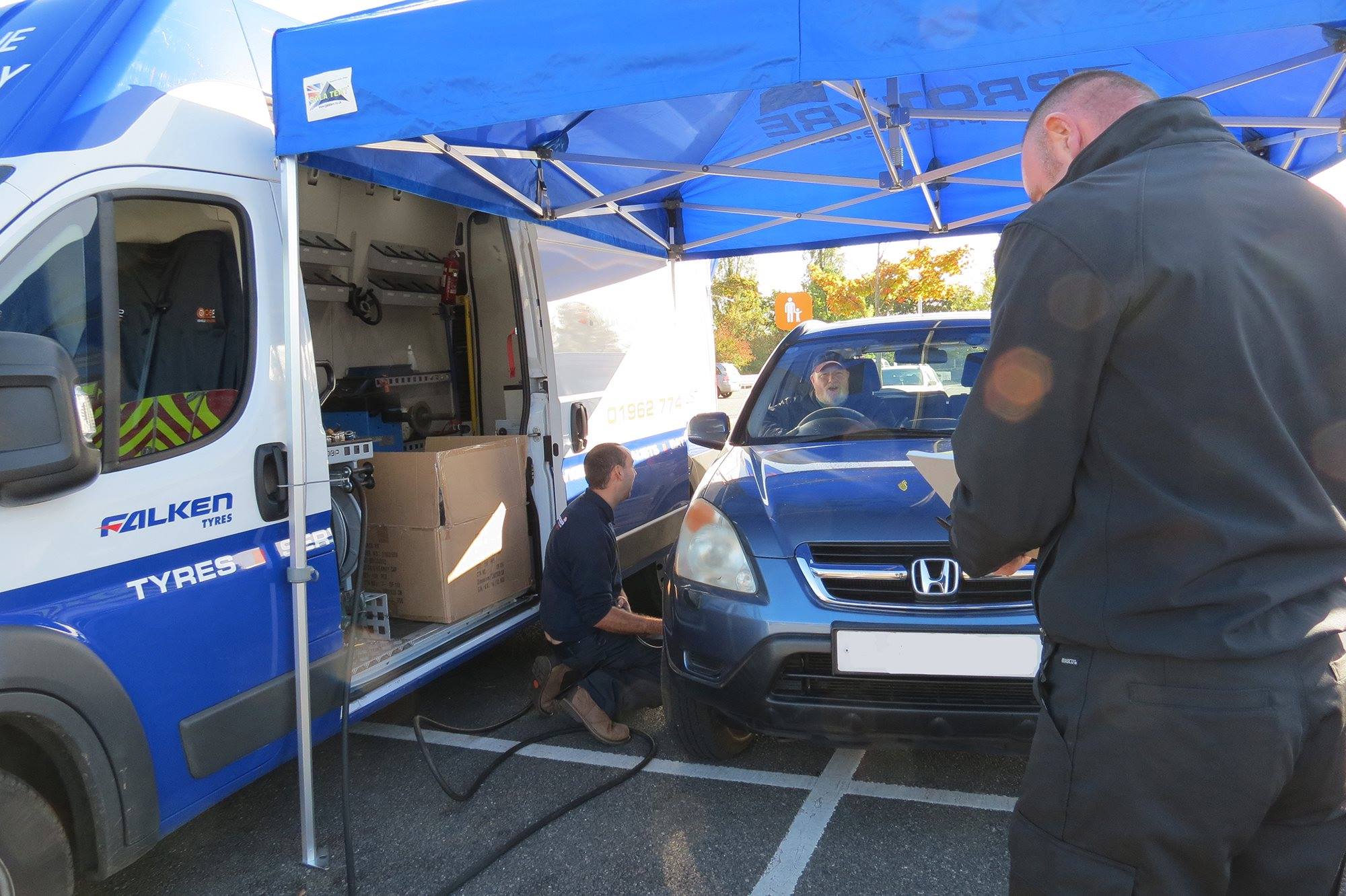 Freestanding race awning set up alongside a motorsport transporter trailer