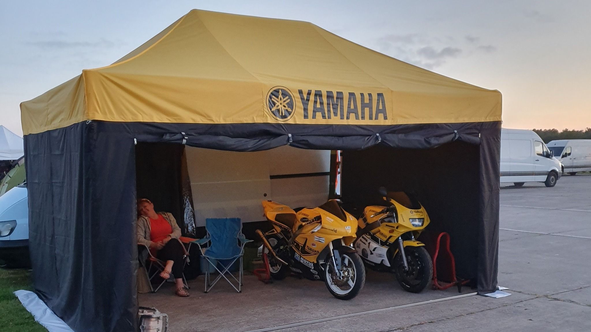 Motorcycle on paddock stands under a race awning at a track day